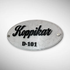 An elegant oval nameplate featuring a marble-style finish with raised black lettering | Koppikar