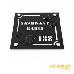 Yashwant Karli square black nameplate, oblique detail of layered flowers, cutout text and four mounting caps