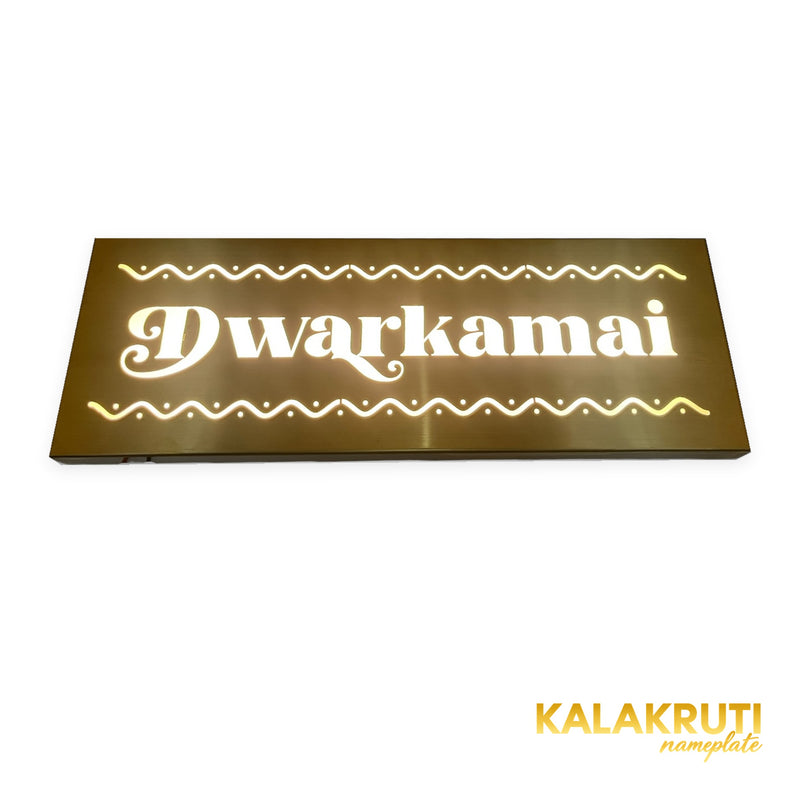 Dwarkamai brushed brass-gold LED nameplate — Low angle warm LED on with original folded return