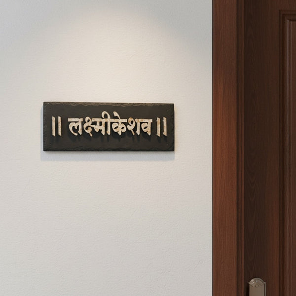 Lakshmikeshav black stone nameplate installed beside an apartment entrance door