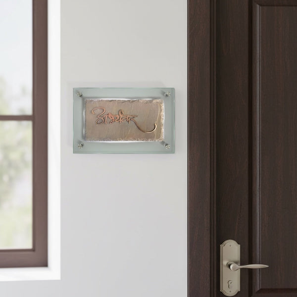 Abhyankar sandstone and copper nameplate with glass backing installed beside an apartment door