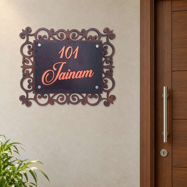 Jainam nameplate shown installed beside an indoor apartment entrance door