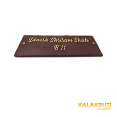 Dinesh Shriram Shah nameplate, low front view showing brass lettering and thin chipped stone edge on a white studio background