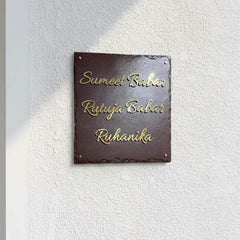 Sumeet and Rutuja Babar brass family nameplate installed on a white textured wall beside an entrance door